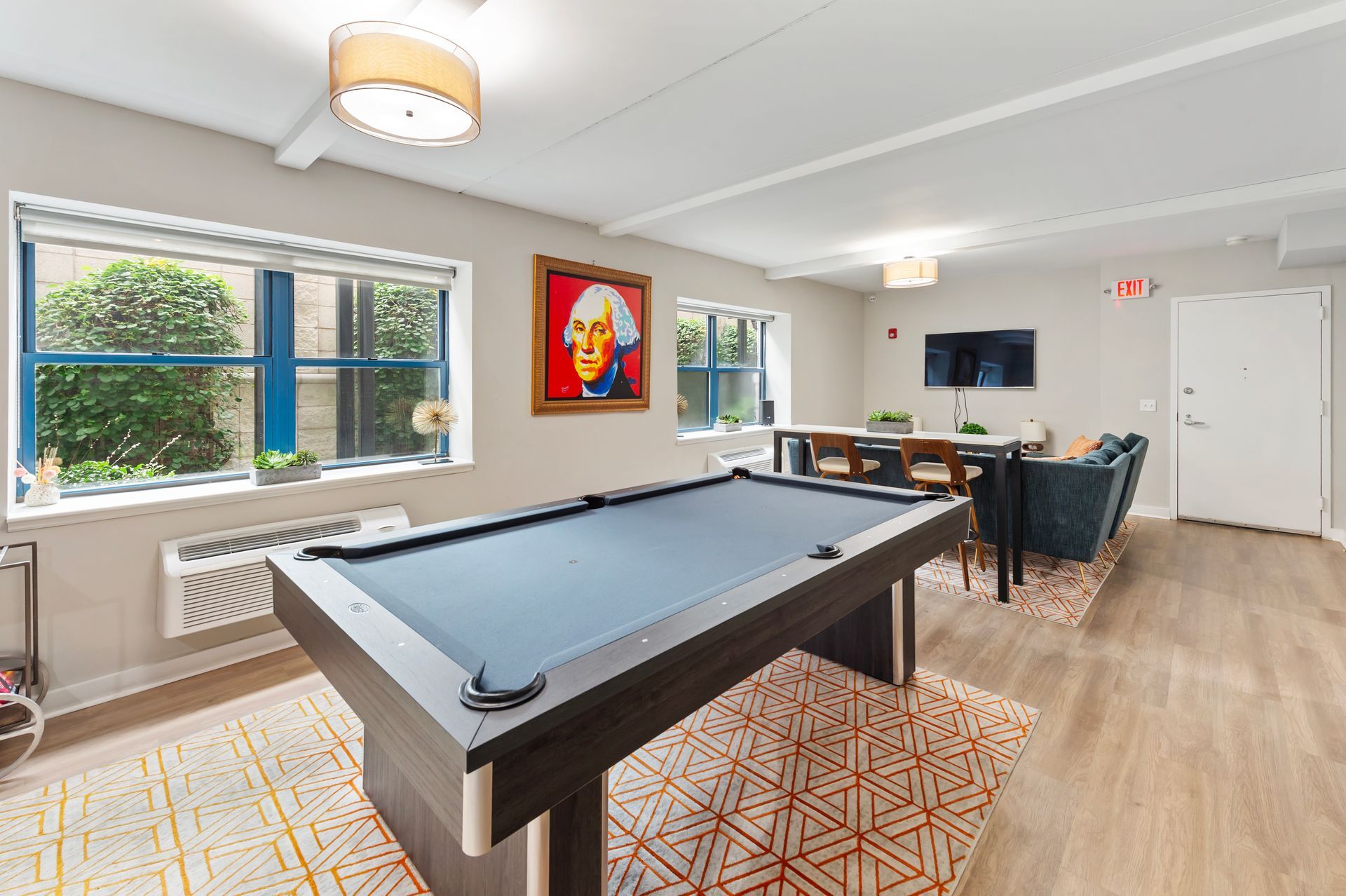 Recreation room with pool table, seating, windows, and a portrait of George Washington.