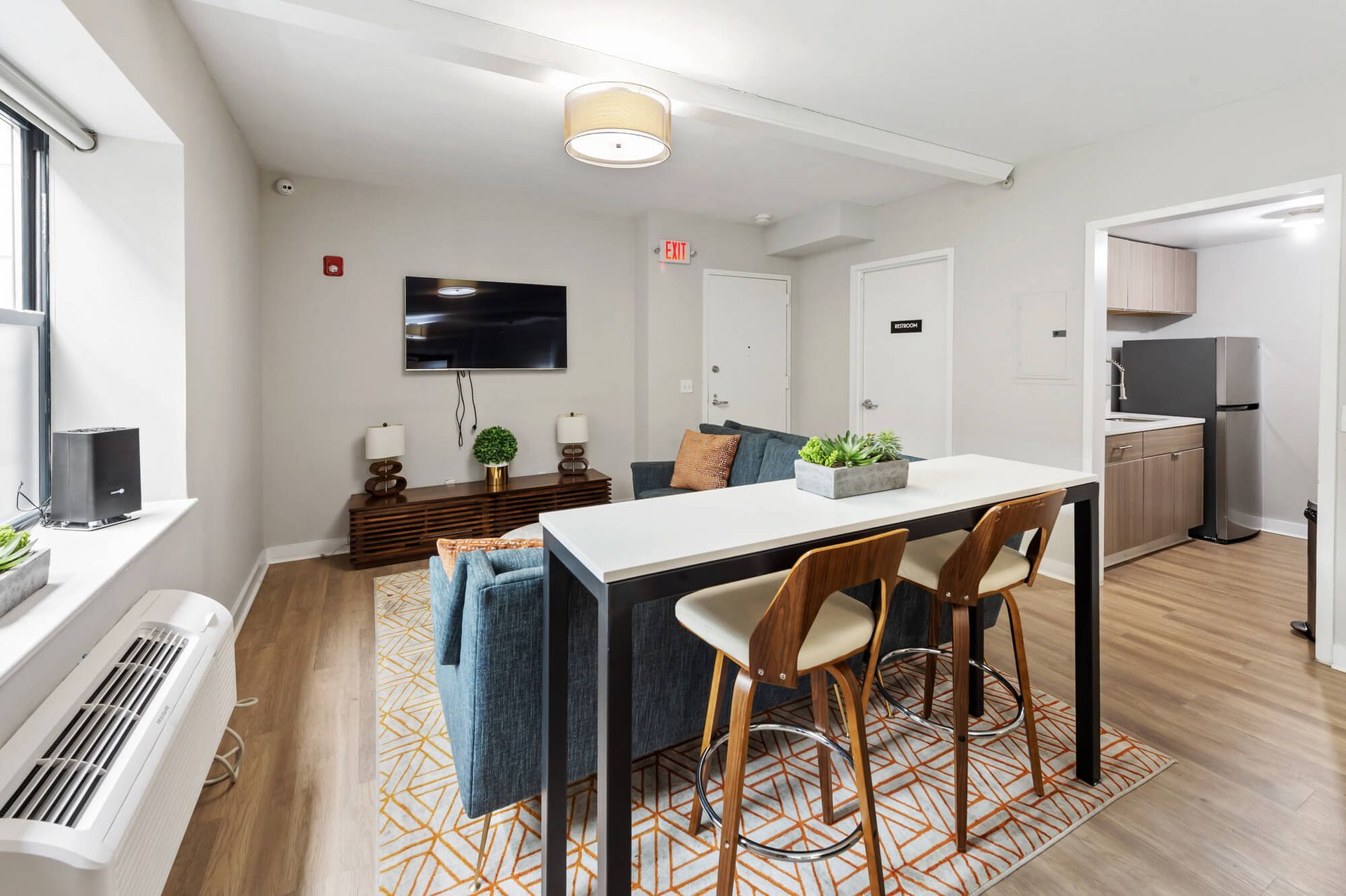 Living area with bar seating, couch, TV, and open doorway to kitchen.