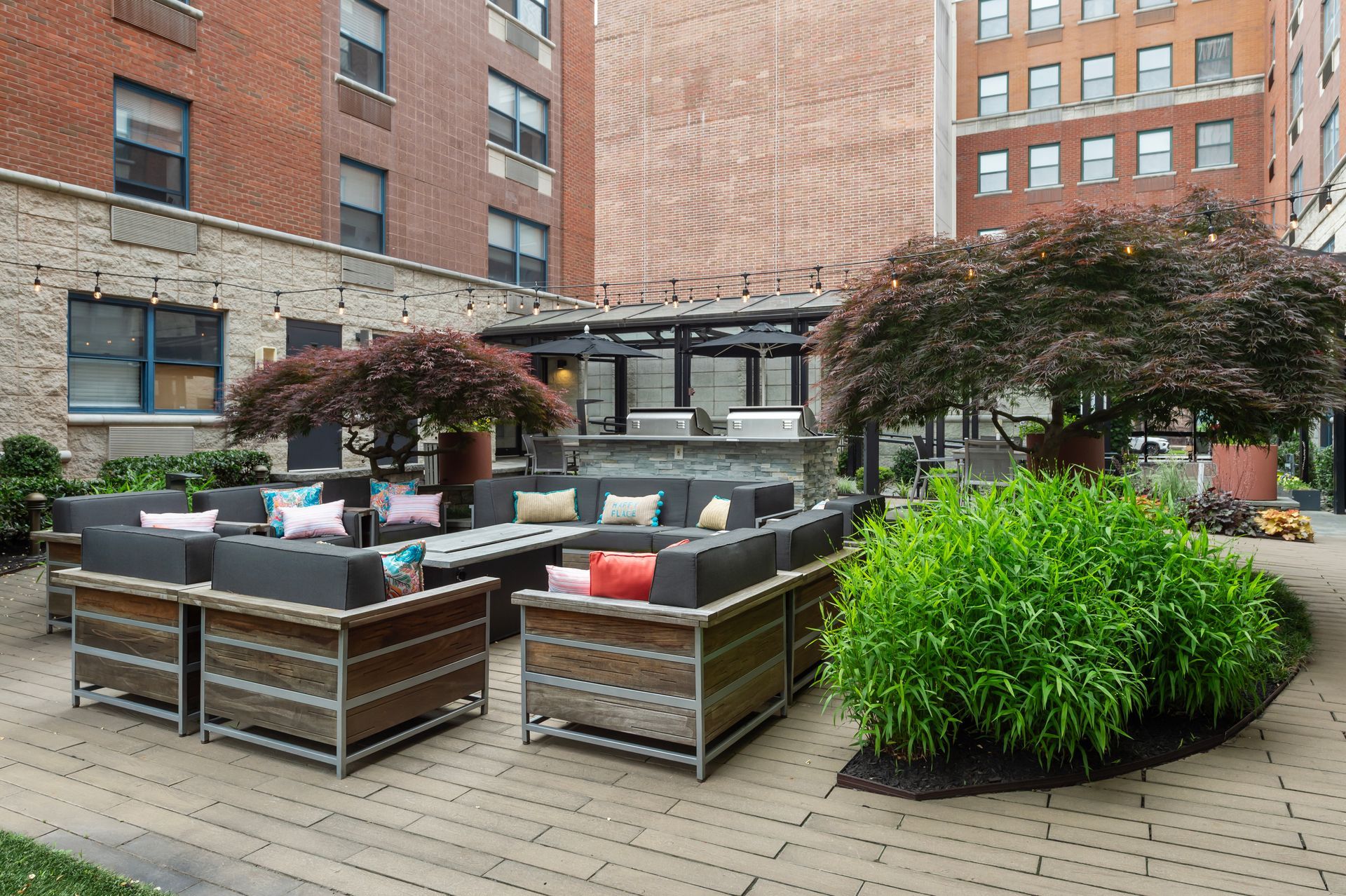 Outdoor lounge area with seating, plants, and brick buildings.
