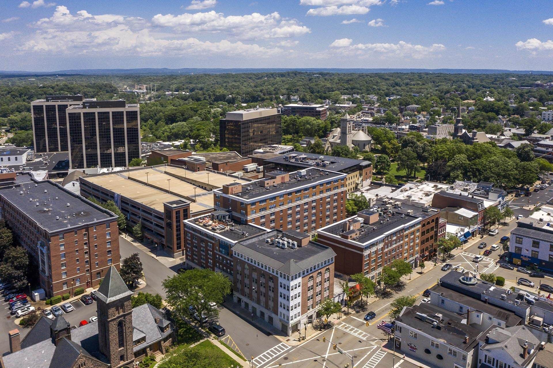 Aerial view of a city with various buildings, including tall office buildings and residential structures, under a clear sky.