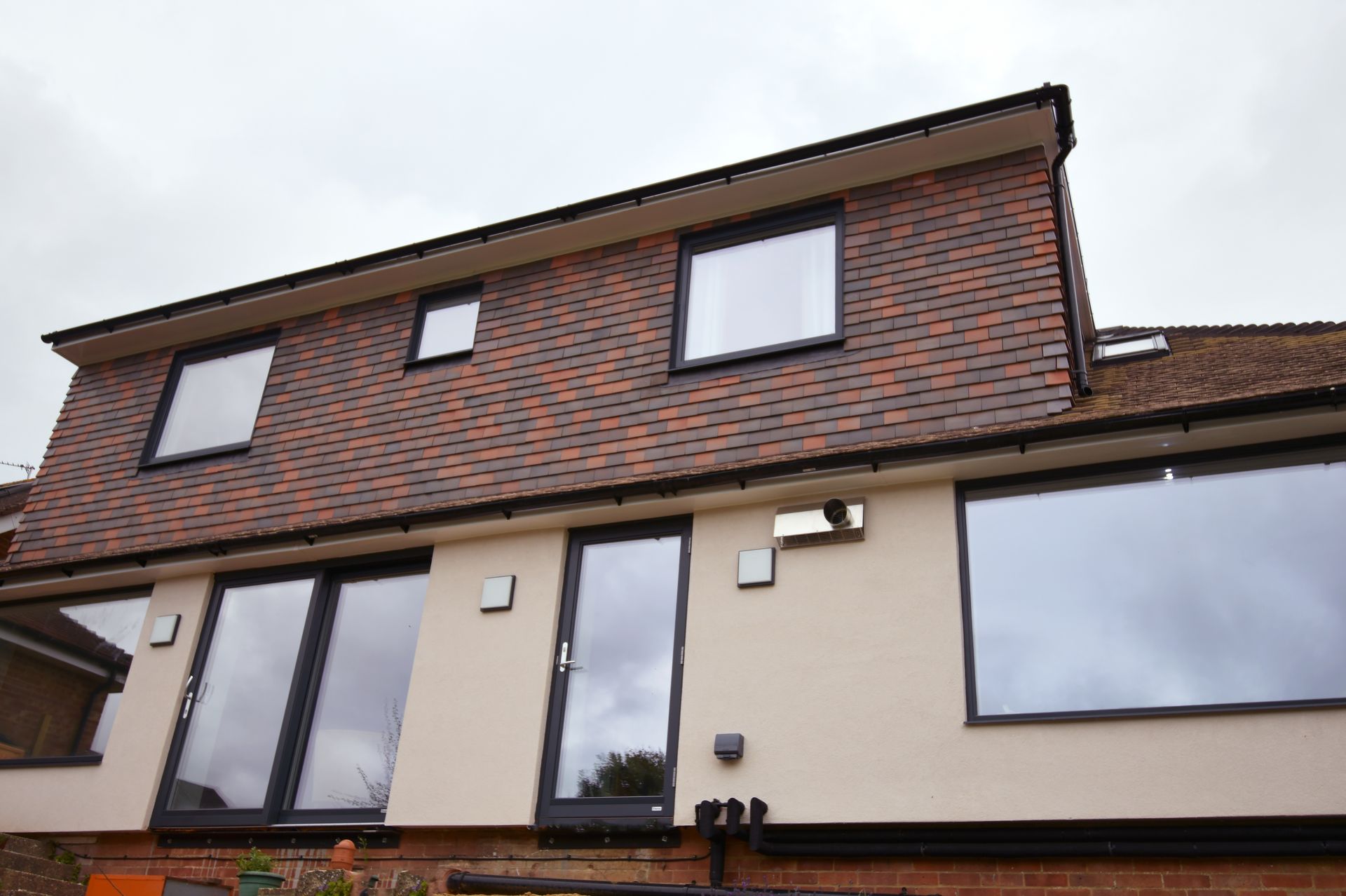 A house with a lot of windows and a brick roof  in a Passivhaus New Builds in East Sussex