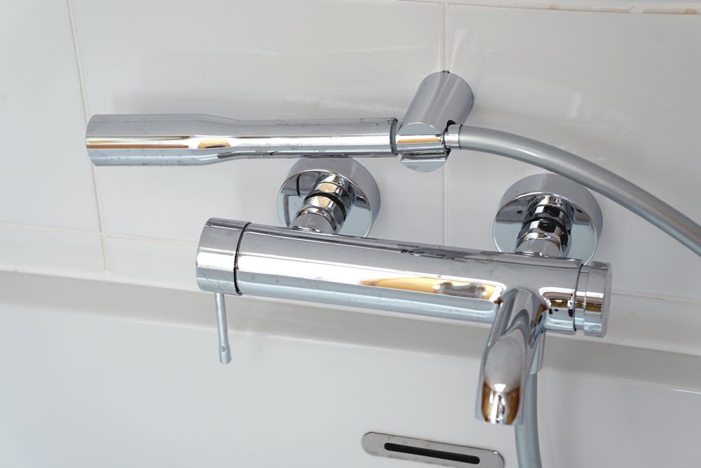 A bathroom faucet with a shower head attached to it  in a Large-Scale Retrofitting in East Sussex