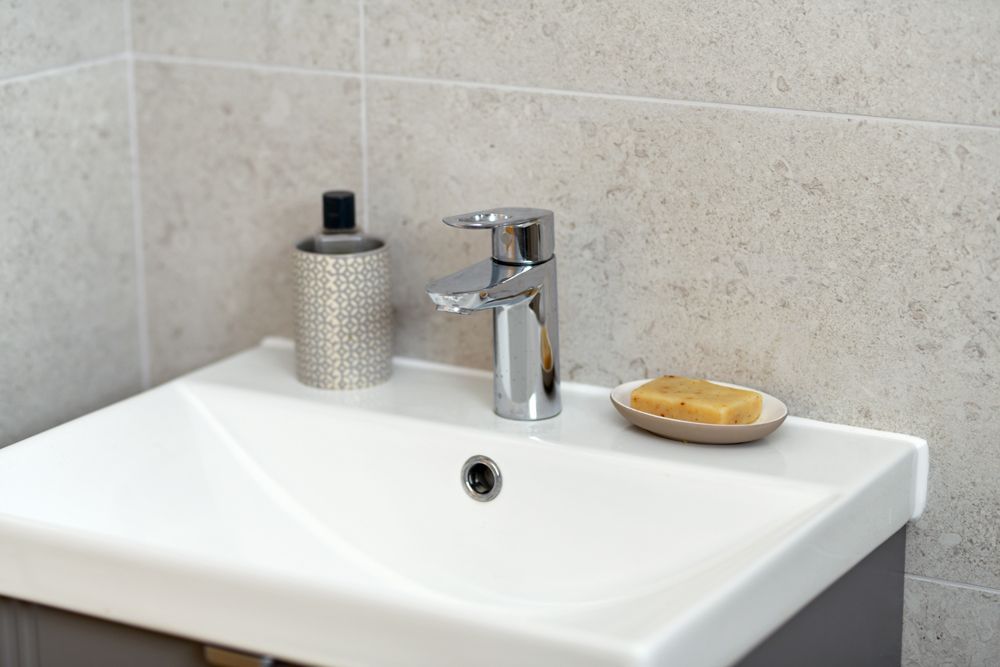 A bathroom sink with a soap dish and a soap dispenser  in a Passivhaus New Builds in East Sussex