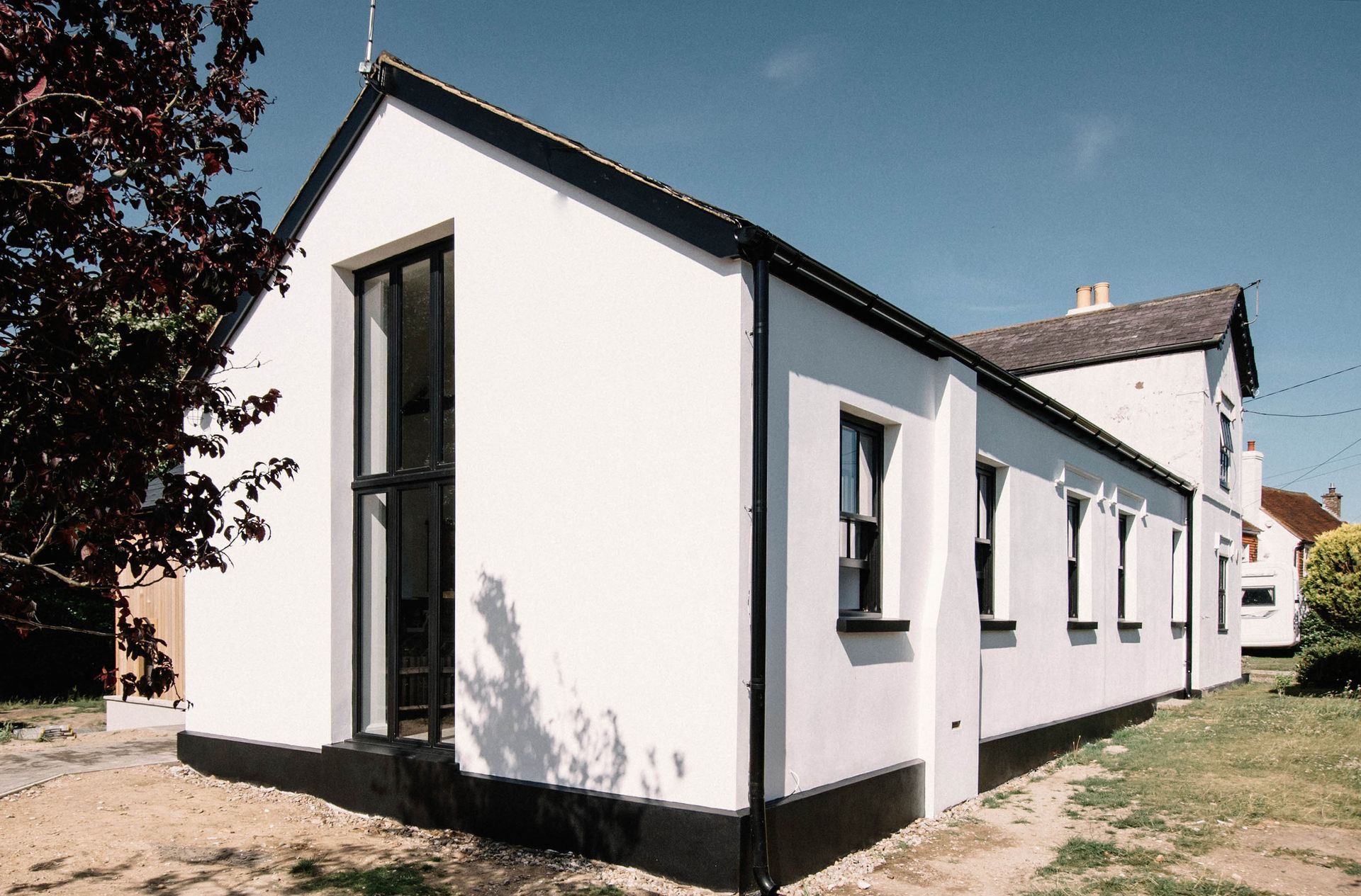 A brick house with a blue door and a large bay window in a Large-Scale Retrofitting in East Sussex