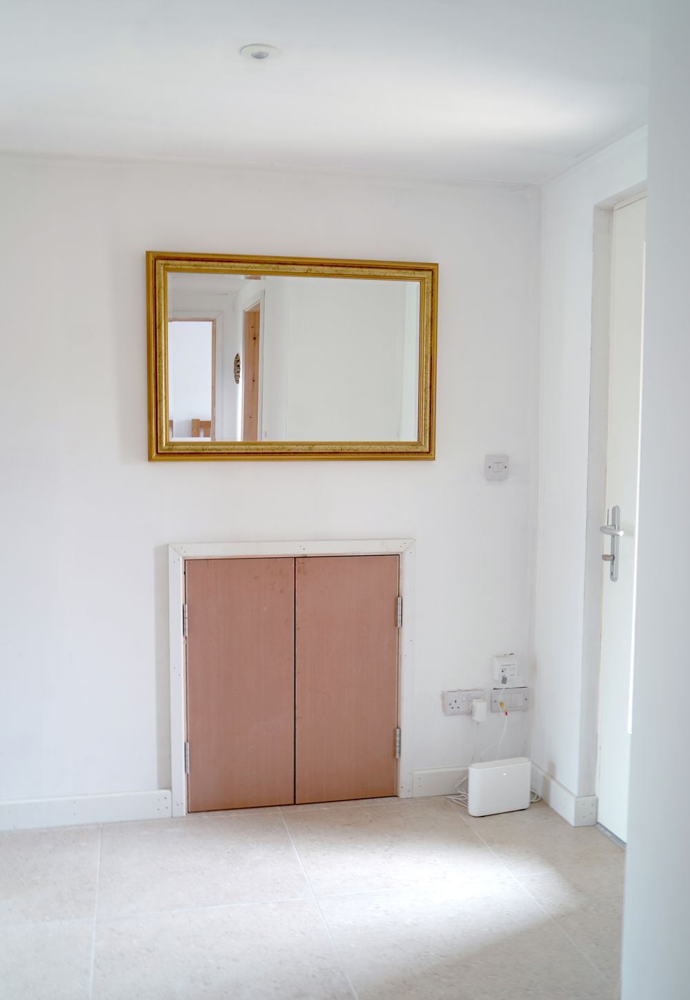 An empty room with a mirror above a doorway  in a Large-Scale Retrofitting in East Sussex