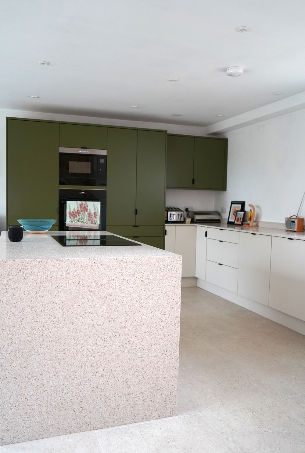 A kitchen with green cabinets and white counter tops  in a Passivhaus New Builds in East Sussex