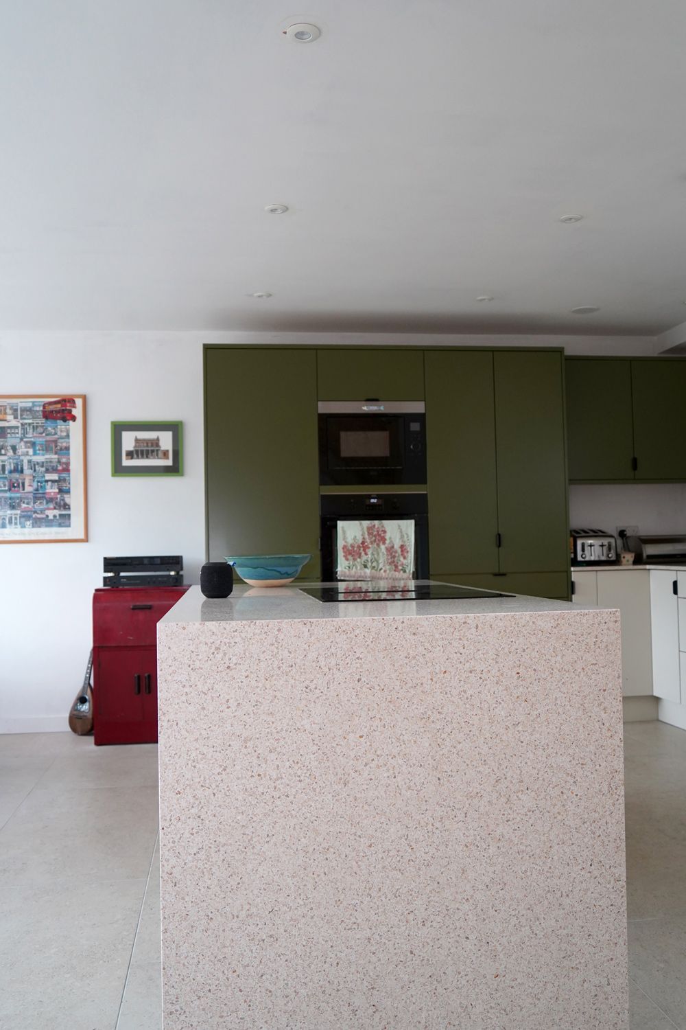 A kitchen with green cabinets and a large island in the middle  in a Retrofit Consultancy in East Sussex