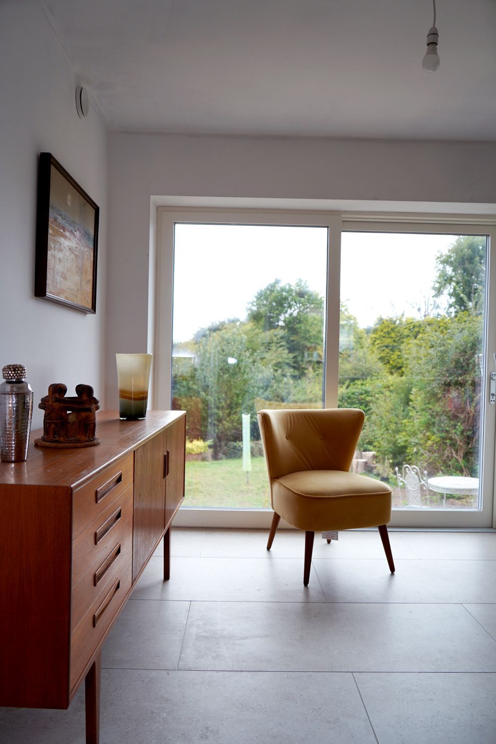 A living room with a chair , dresser , and sliding glass door  in a Passivhaus New Builds in East Sussex