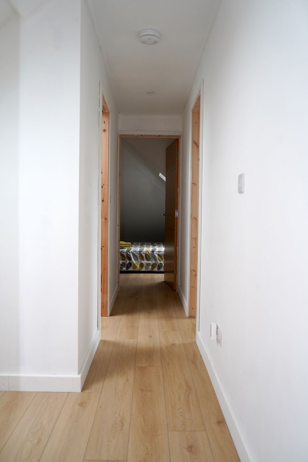 A long hallway with wooden floors and white walls leading to a bedroom  in a Construction Management in East Sussex