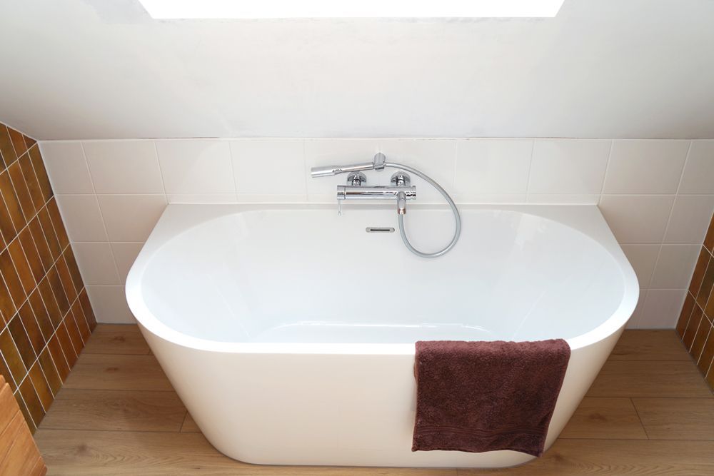 A bathtub in a bathroom with a skylight above it  in a Large-Scale Retrofitting in East Sussex