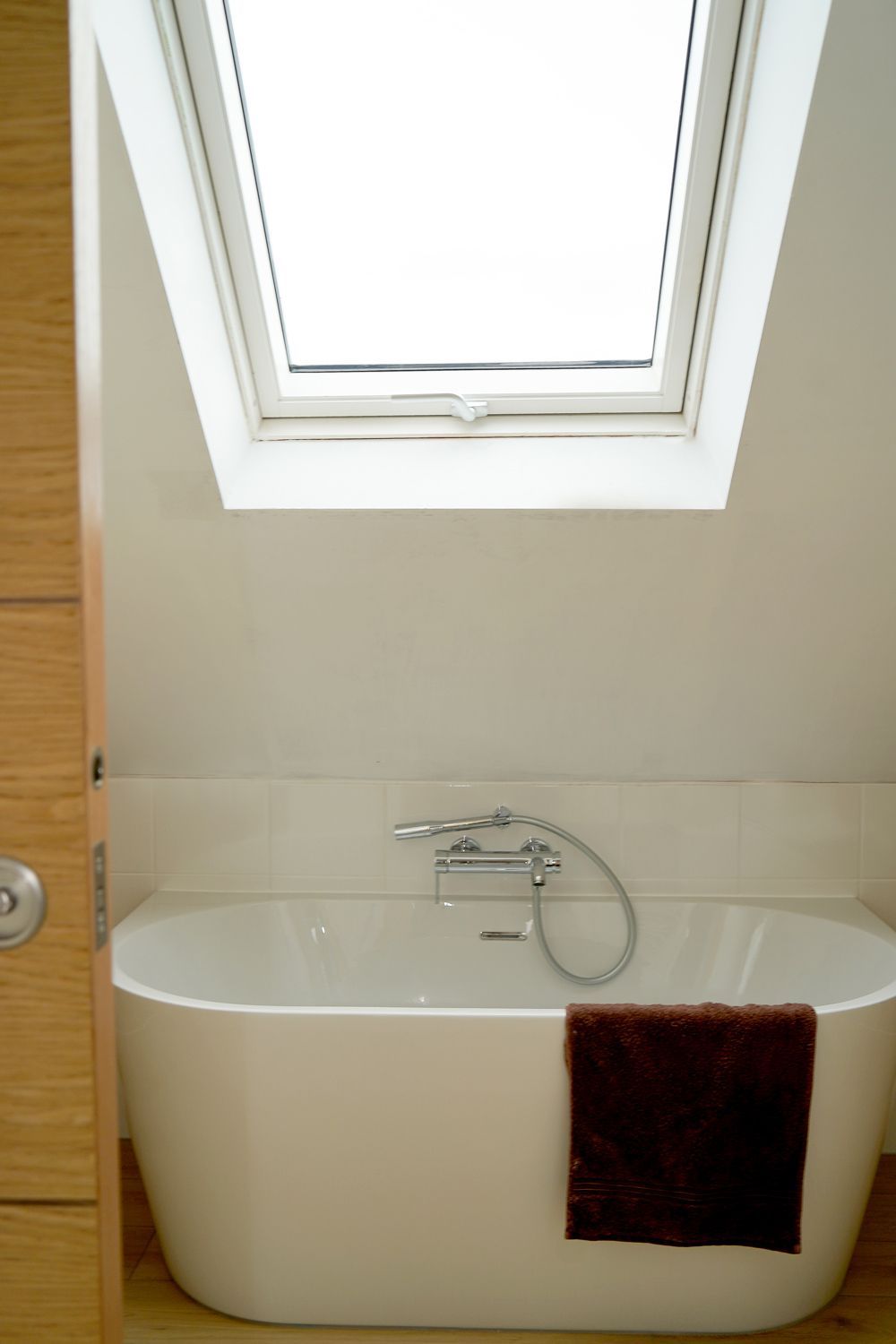 A bathtub under a skylight in a bathroom  in a Large-Scale Retrofitting in East Sussex