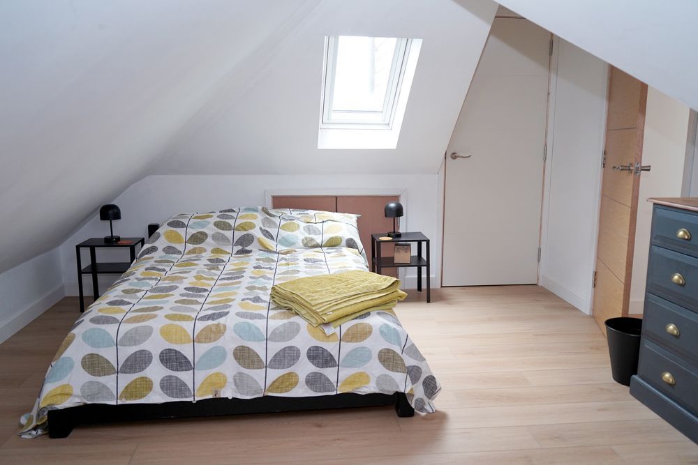 A bedroom with a bed , dresser , nightstands and a skylight  in a Retrofit Consultancy in East Sussex