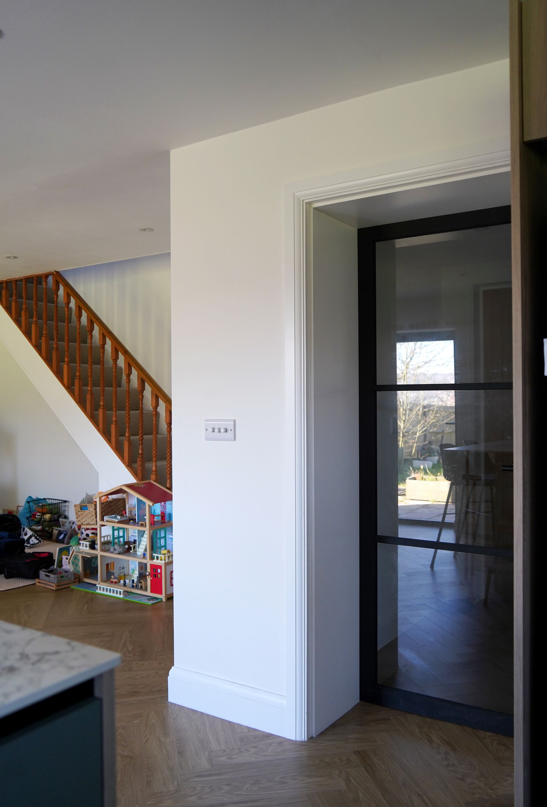 A staircase with a glass railing and a wooden handrail in a house in a Large-Scale Retrofitting in Battle