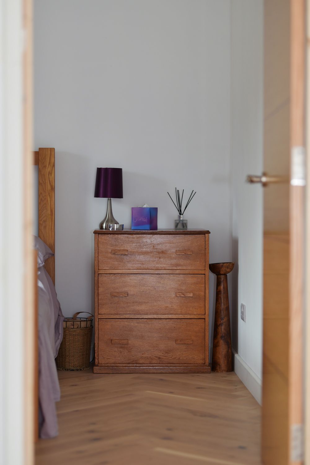 A bedroom with a wooden dresser and a lamp  in a Passivhaus New Builds in East Sussex