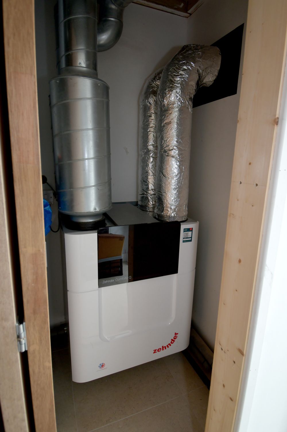 A white air conditioner is sitting in a closet next to a door  in a Construction Management in East Sussex