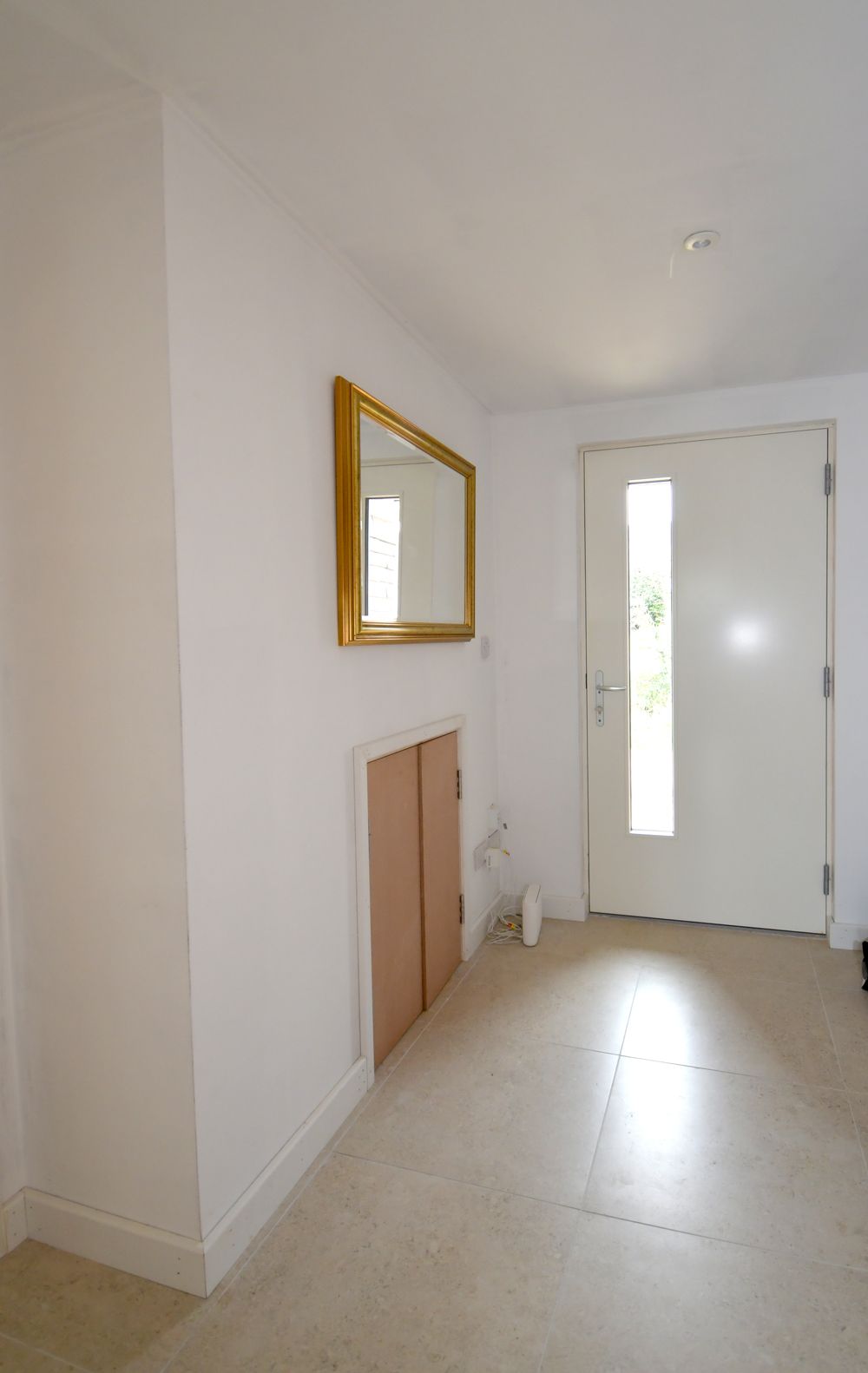 A hallway with a door and a mirror on the wall  in a Construction Management in East Sussex