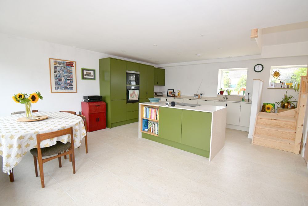 A kitchen with green cabinets and a table and chairs  in a Passivhaus New Builds in East Sussex