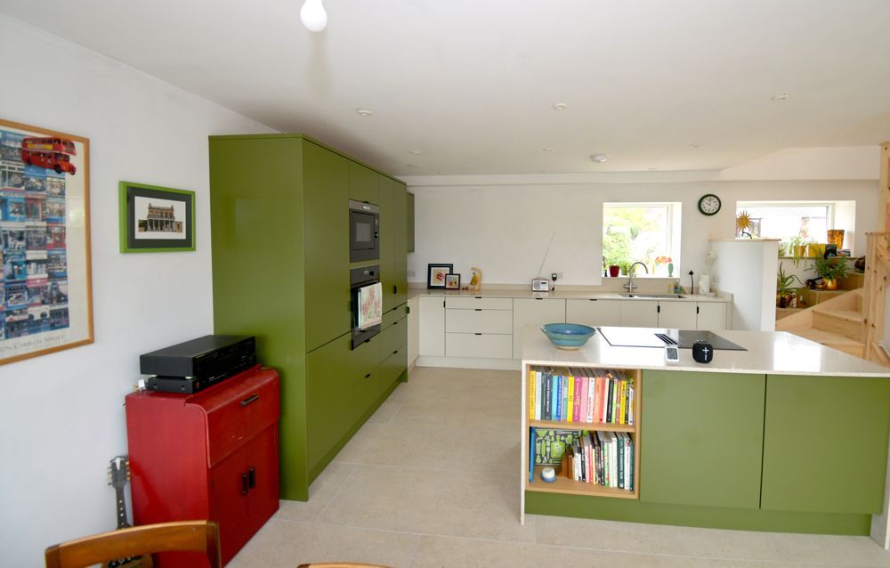 A kitchen with green cabinets and a red dresser  in a Passivhaus New Builds in East Sussex