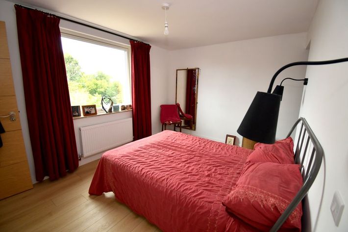 A bedroom with a red bed and red curtains  in a Retrofit Consultancy in East Sussex