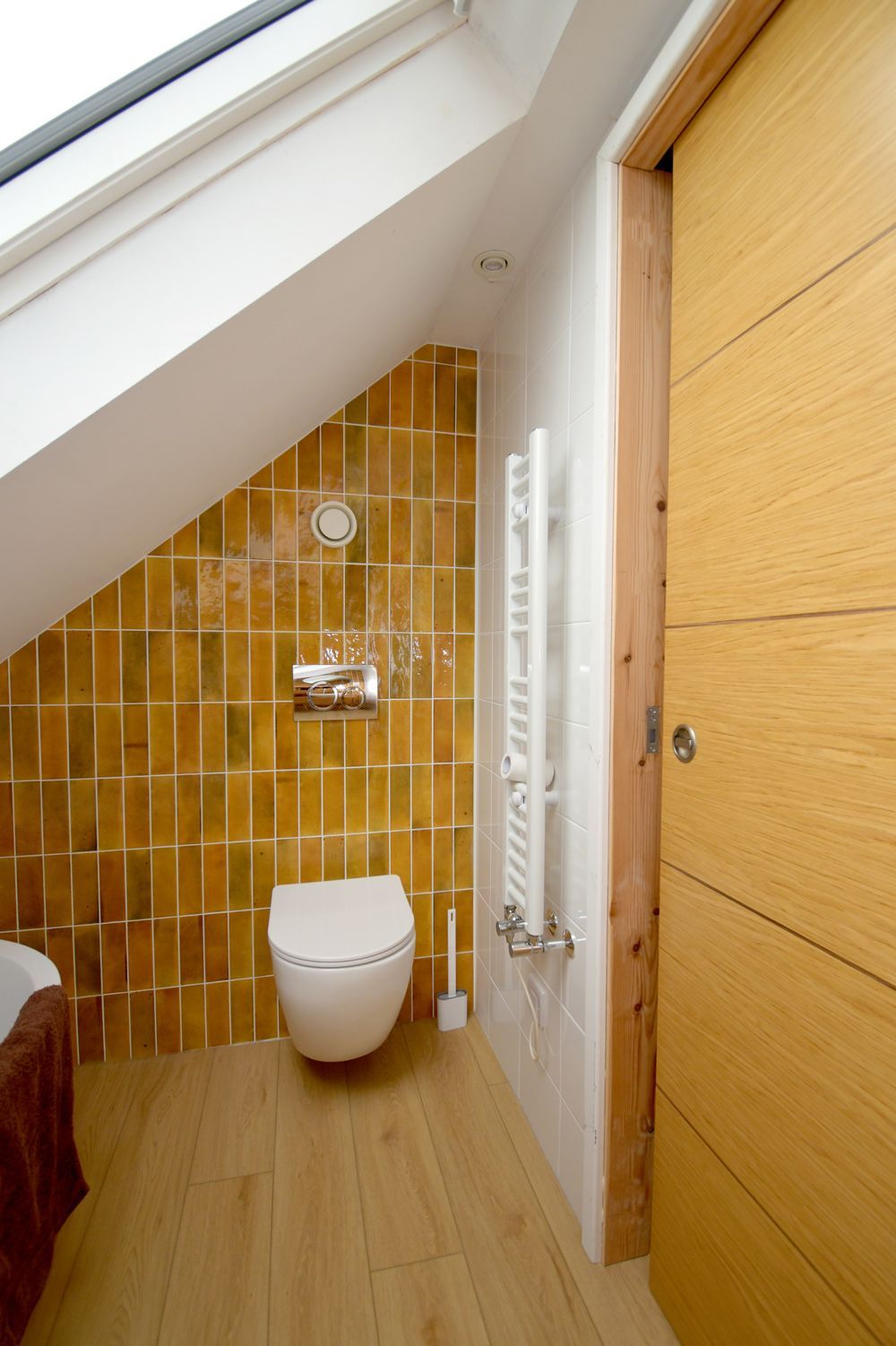 A bathroom with a toilet and a wooden door  in a Large-Scale Retrofitting in East Sussex