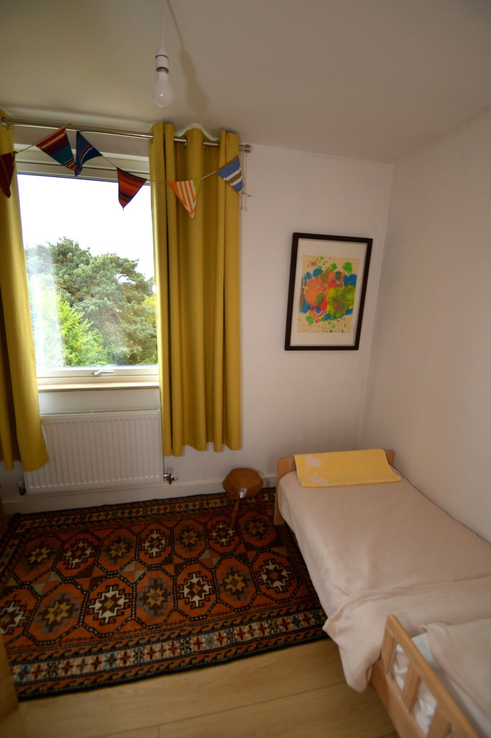 A bedroom with a single bed , a rug , a window and a picture on the wall  in a Retrofit Consultancy in East Sussex