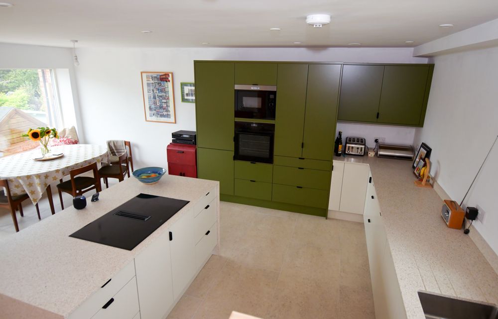 A kitchen with green cabinets and white counter tops  in a Passivhaus New Builds in East Sussex