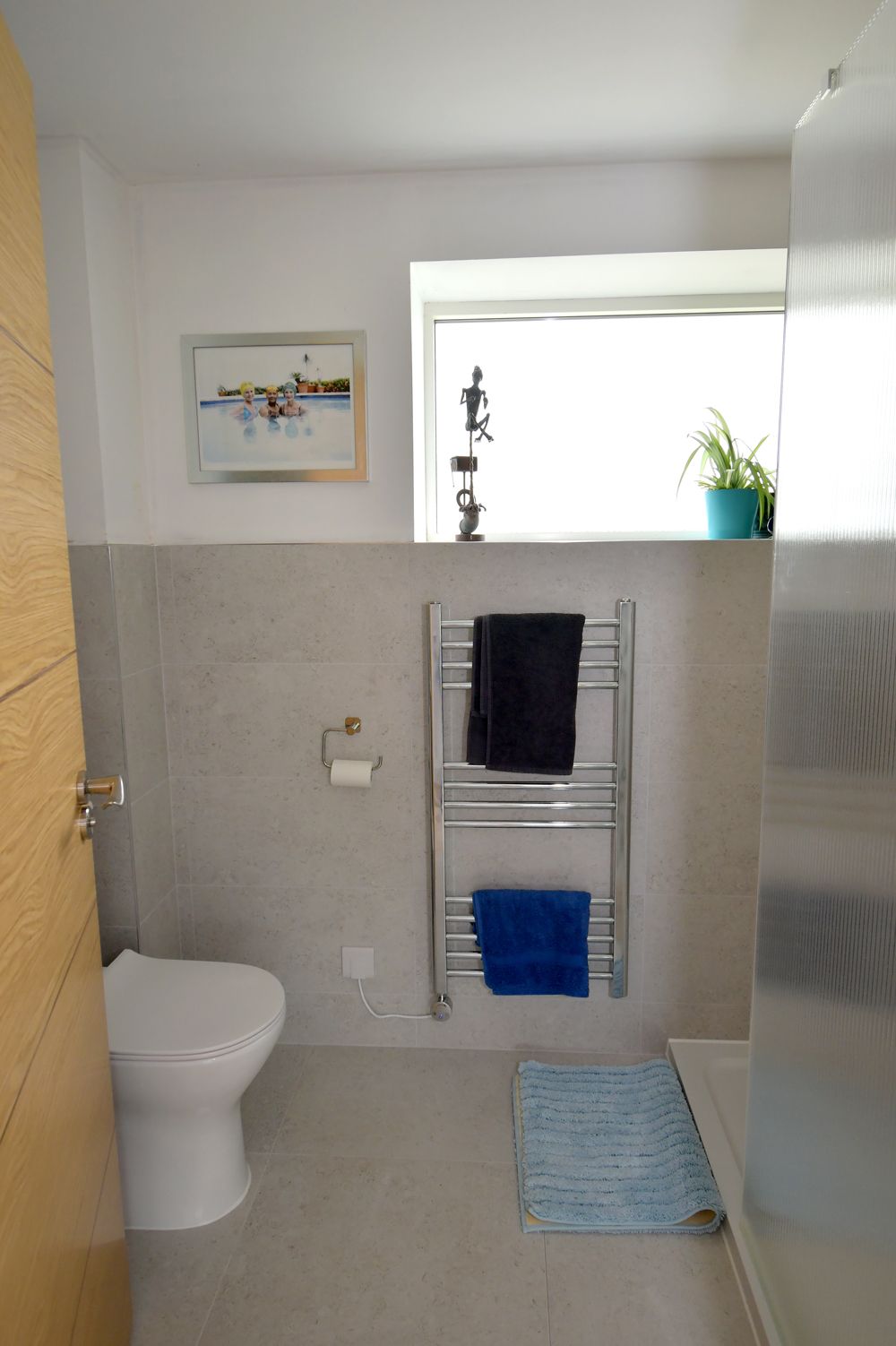 A bathroom with a toilet a towel rack and a window  in a Passivhaus New Builds in East Sussex