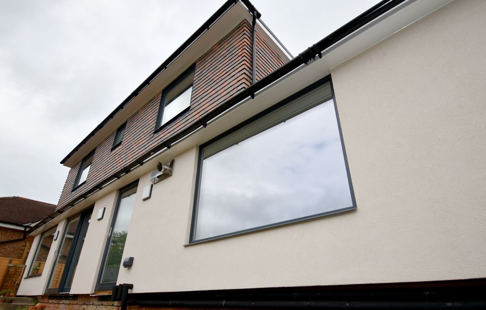 A house with a large window on the side of it  in a Large-Scale Retrofitting in East Sussex