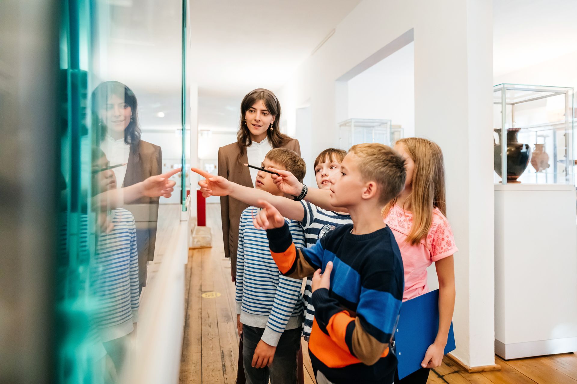 A group of children are looking at a glass wall in a museum.