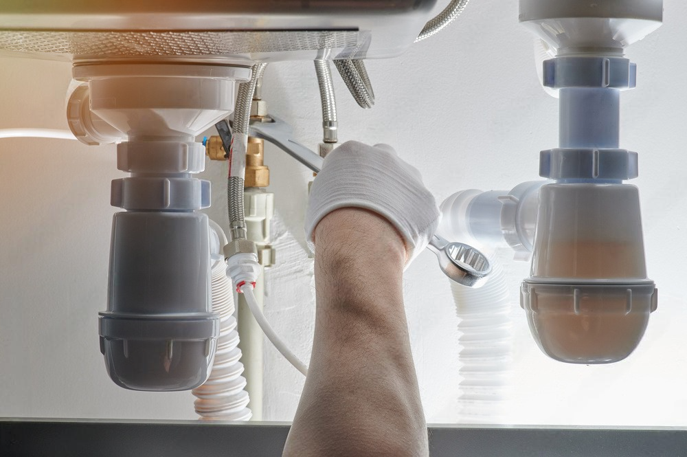 a plumber is fixing a sink with a wrench.