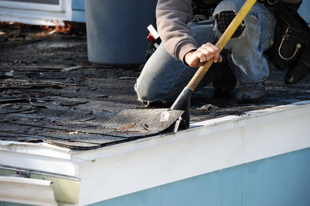 a man is using a shovel to remove shingles from a roof