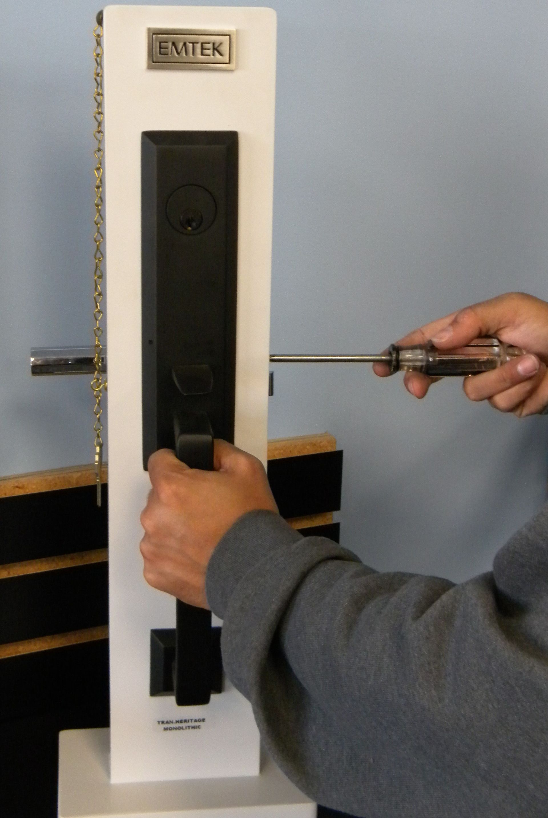 Charm’s Security locksmith showing a decorative Emtek front door handleset using a screwdriver on a display mount.