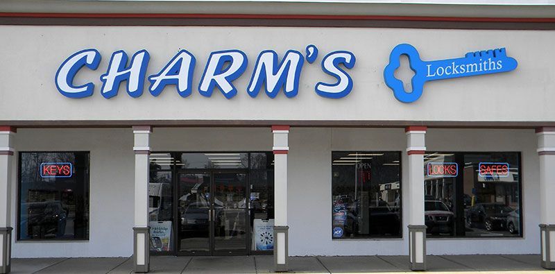 Storefront of Charm’s Locksmiths with large blue signage and front windows displaying keys and safes.