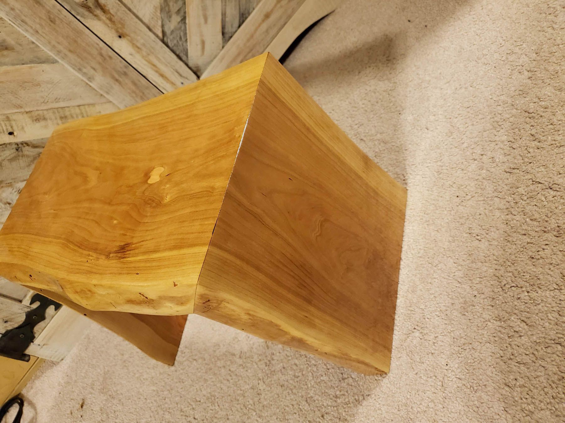 Wooden, angular table with natural edge, on carpet.