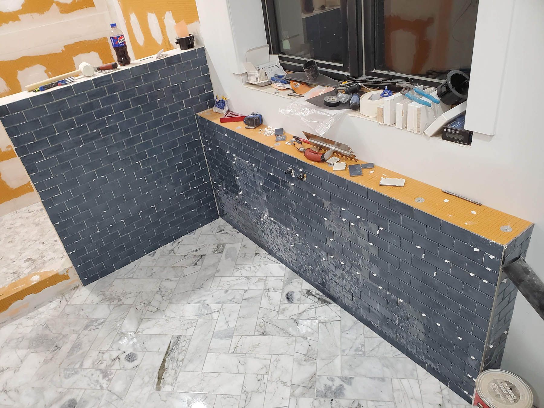 Bathroom under construction, featuring dark gray tile installation.