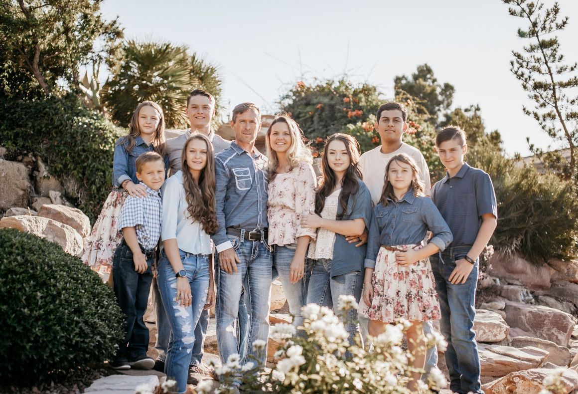 A large family is posing for a picture in a park.