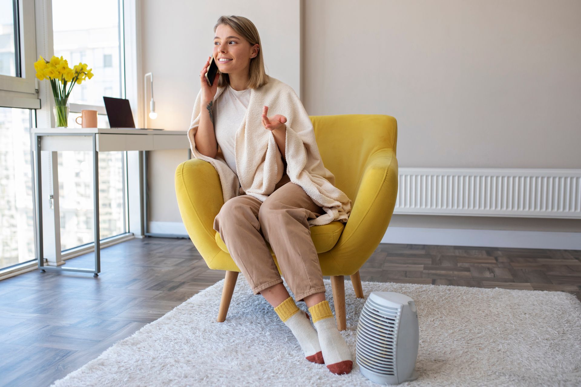 A woman is sitting in a yellow chair talking on a cell phone.