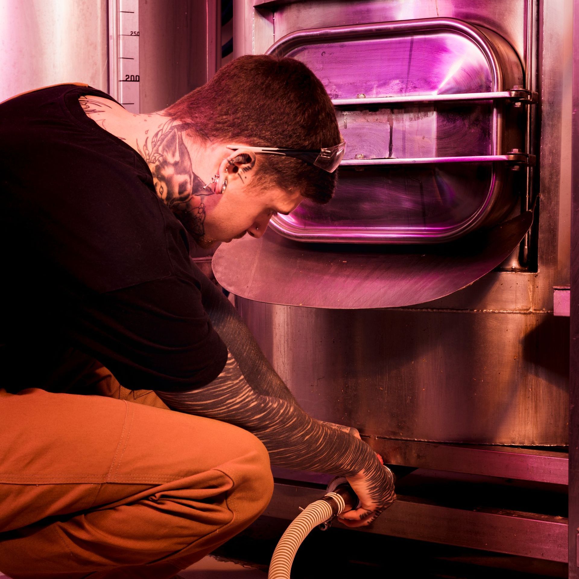 A man is kneeling down in front of a stainless steel oven