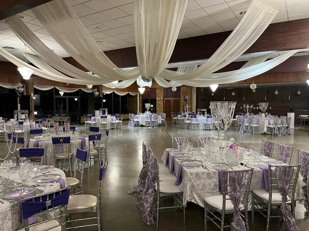 A large room with tables and chairs set up for a wedding reception.