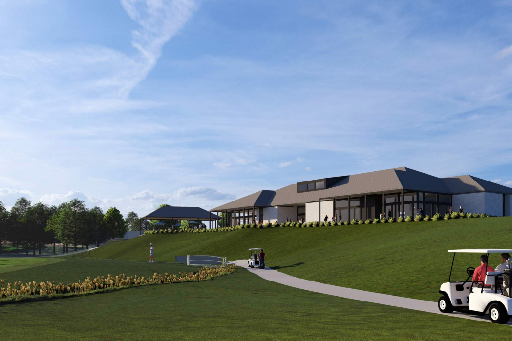 Golf course clubhouse with a golf cart on a path, rolling green hills and blue sky.