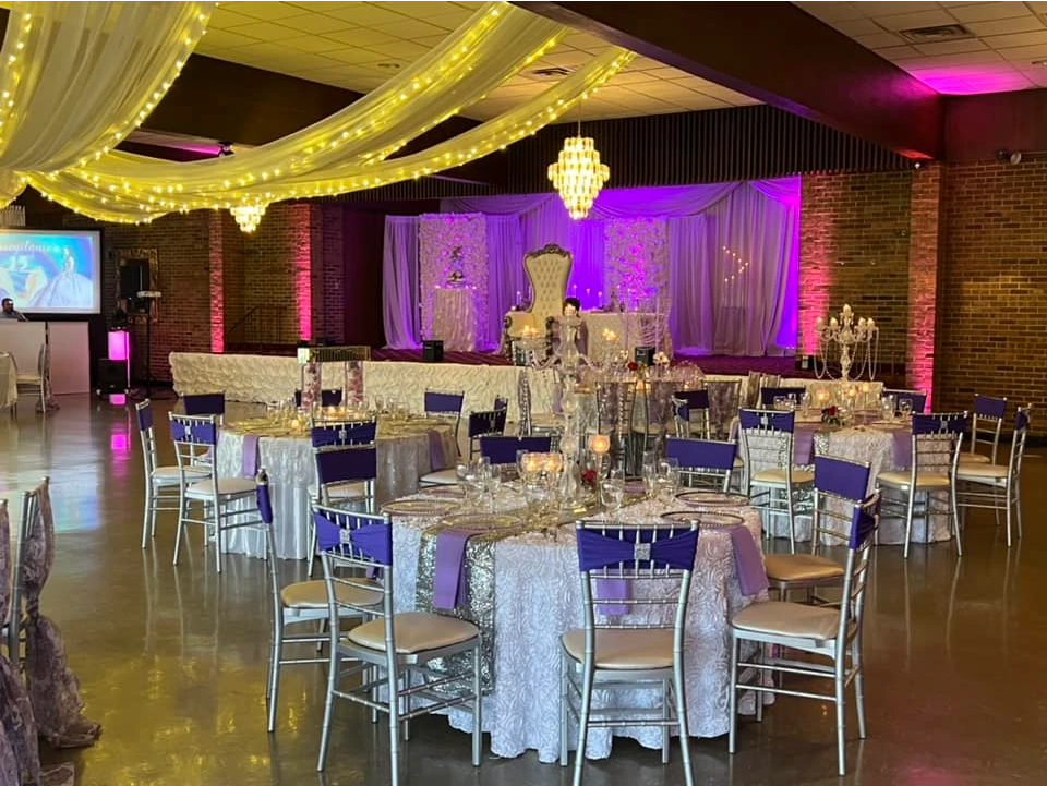 A large room with tables and chairs set up for a wedding reception.