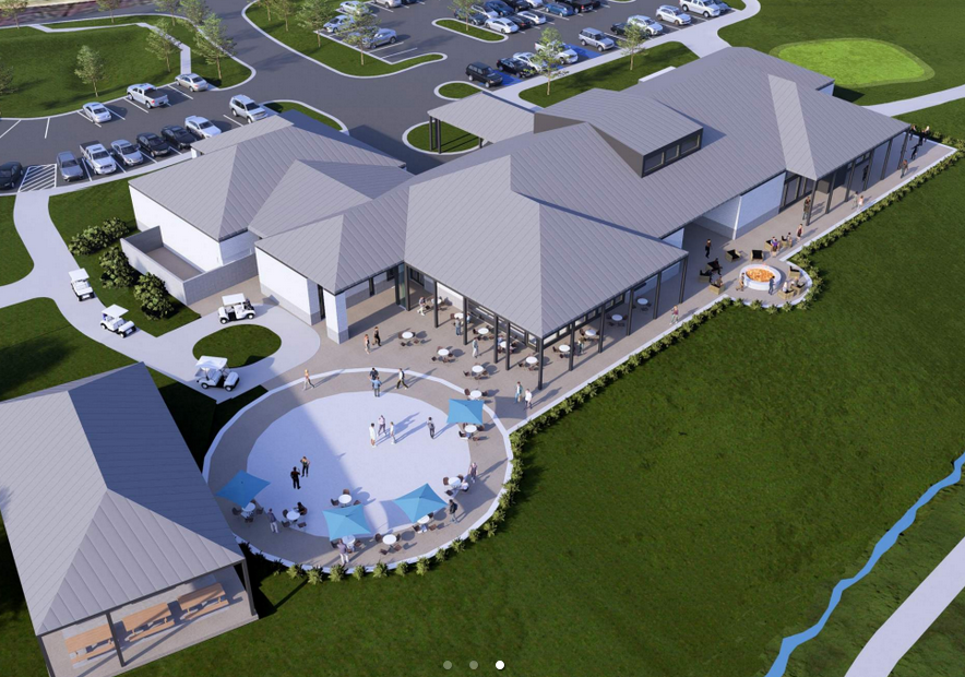 Aerial view of a modern building with a large patio, parking lot, and green lawn.