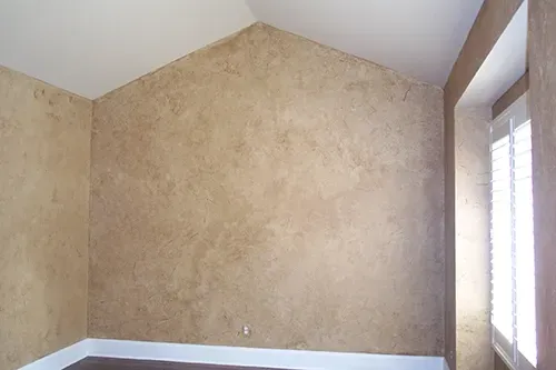 Beige textured walls in a room with a white ceiling, dark floor, and shuttered window.