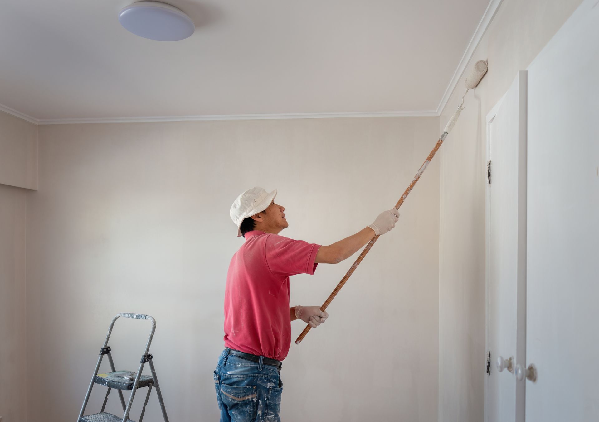 A man is painting a wall with a roller in a home renovation project. A man is painting a wall with a roller in a home renovation project.