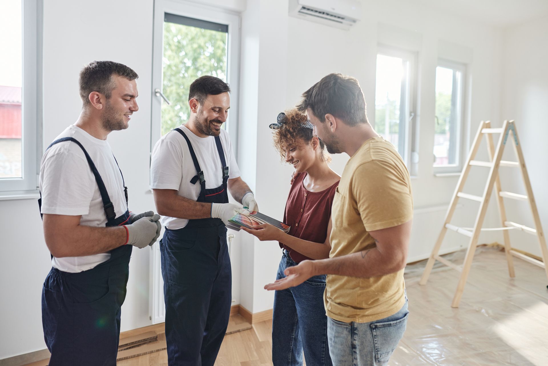 Homeowners paying professional painters after completing interior renovation work in bright room.