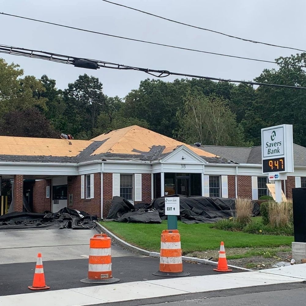 A brick Savers Bank building under construction with exposed roof decking, surrounded by orange traffic cones and barriers.