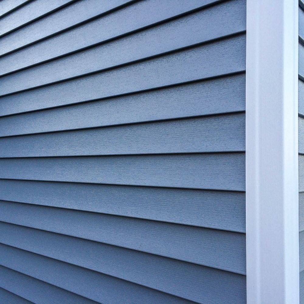 Light blue horizontal lap siding on a house wall with a white vertical corner trim piece.