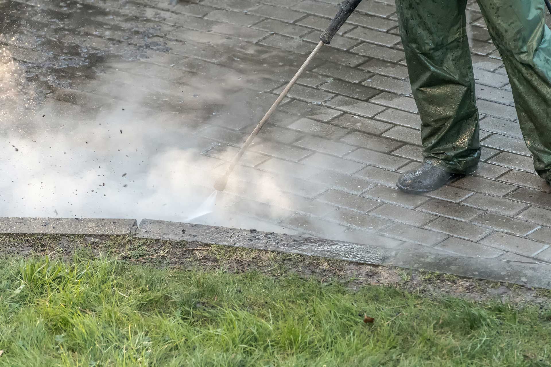 
Worker cleaning driveway with high pressure water jet