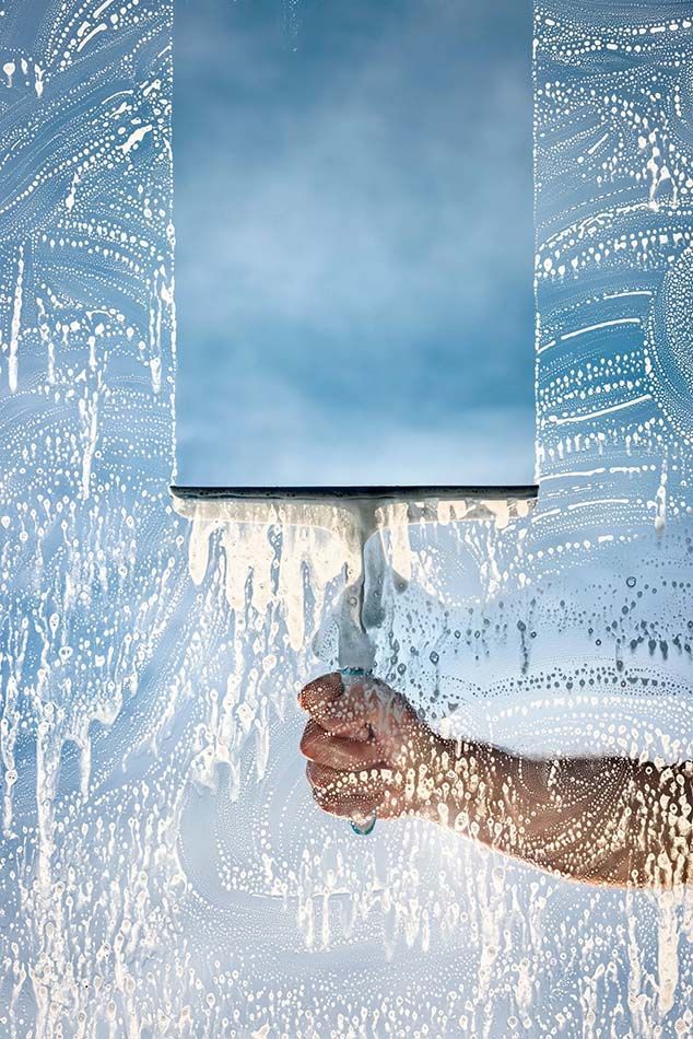 A person is cleaning a window with a squeegee.