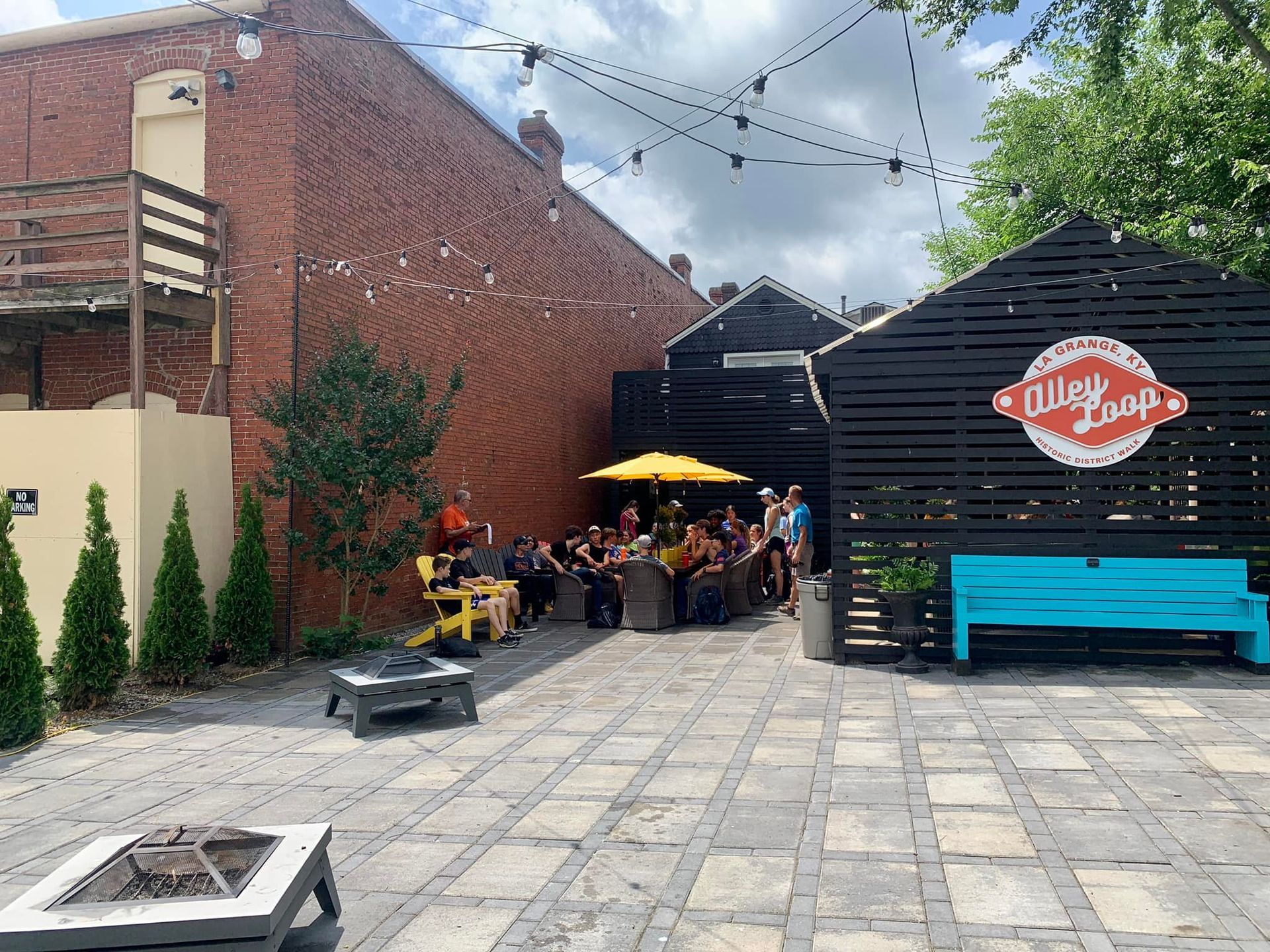 A group of people are sitting at tables in a courtyard in front of a building.
